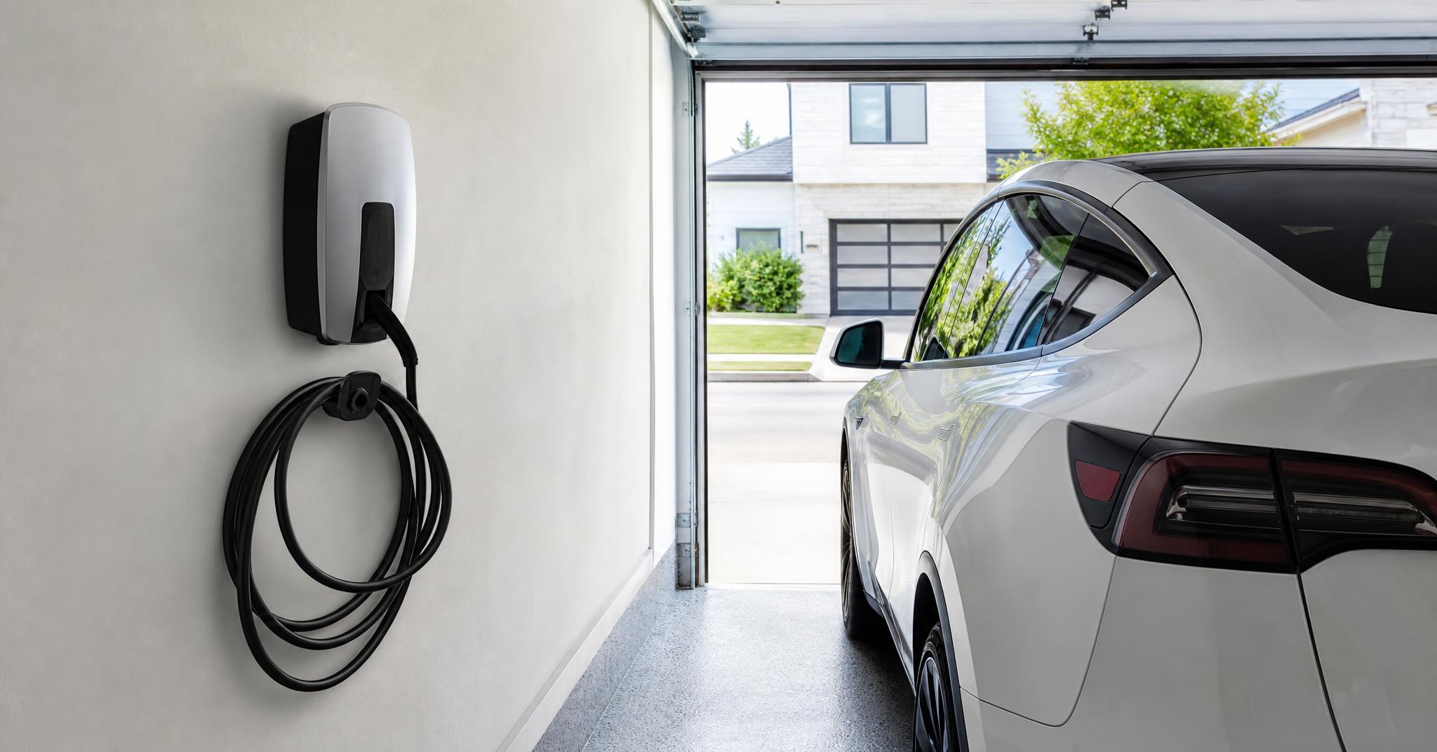 Wall-mounted EV charger installed in a clean residential garage with the cable coiled on its hook.